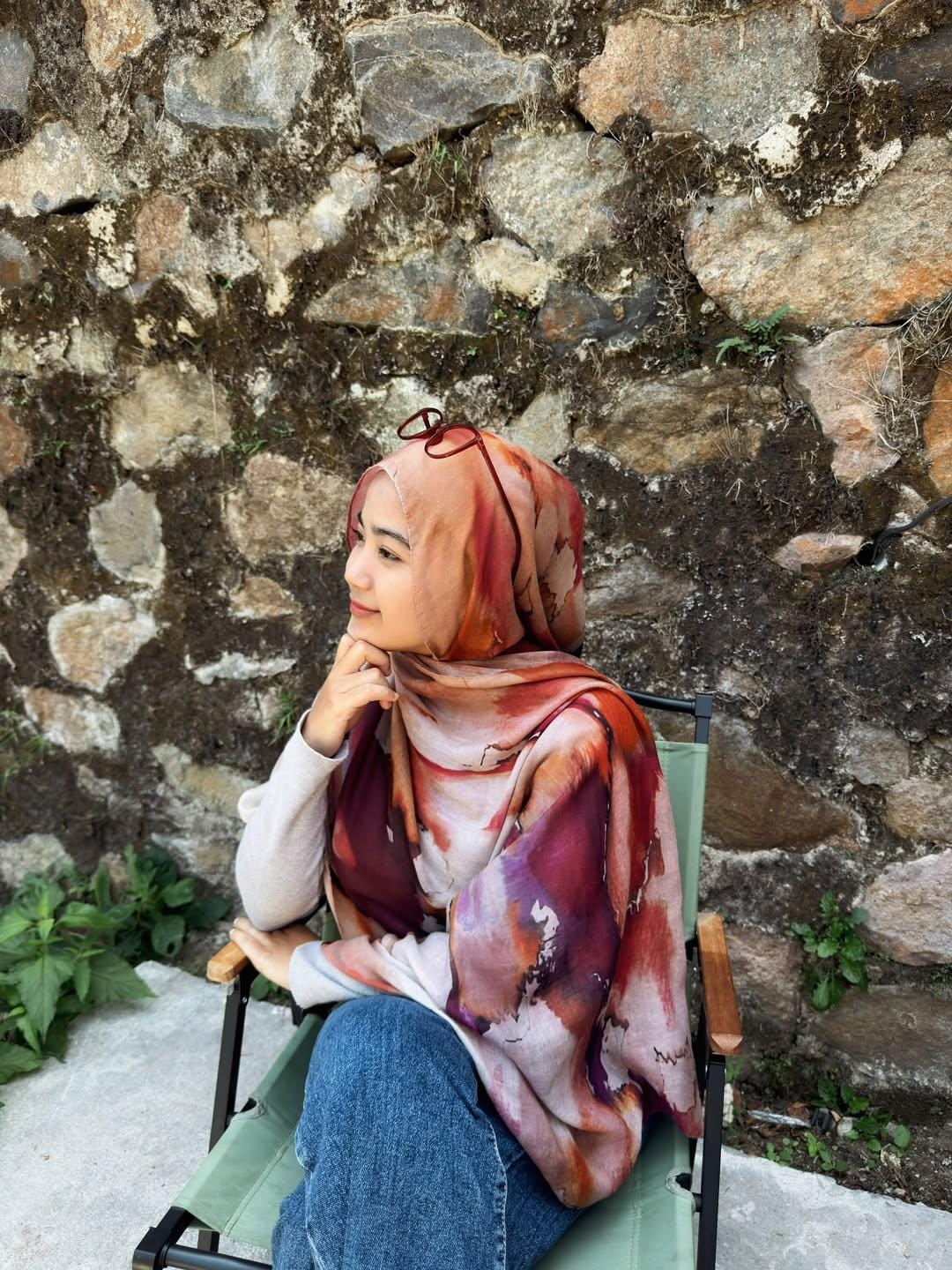 Foto Ridha Fajriah duduk di depan dinding batu